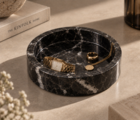 Black marble catchall tray holding rings and jewelry